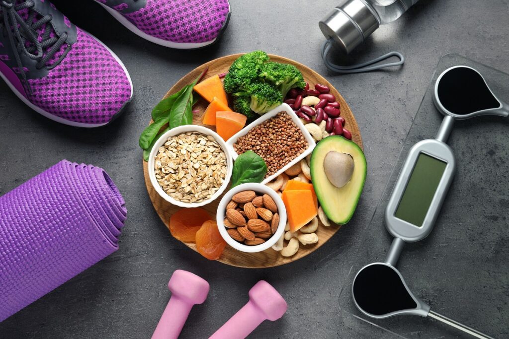 Plate with heart-healthy products and sports equipment on grey b